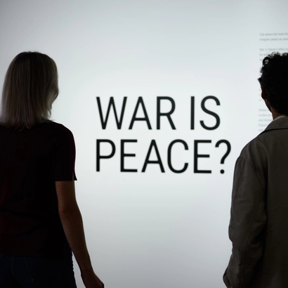 two people in front of the war is peace sign in the exhibition