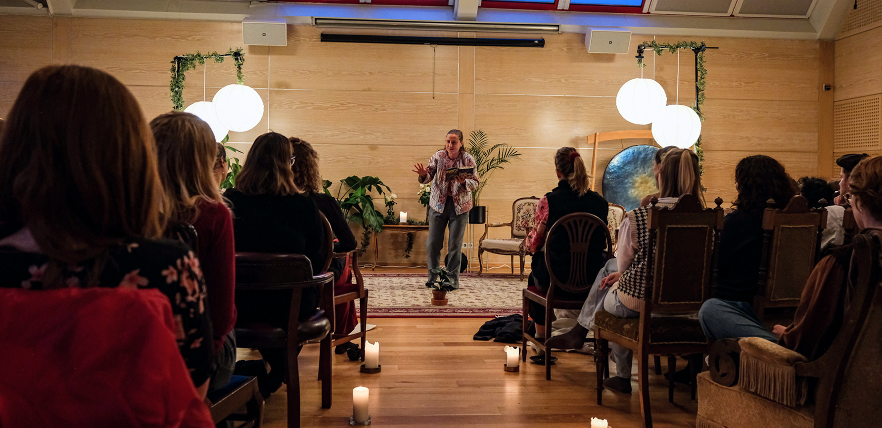 poetry evening, people watching and candles and a person performing.