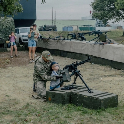 A boy being shown how to use a machine weapon.