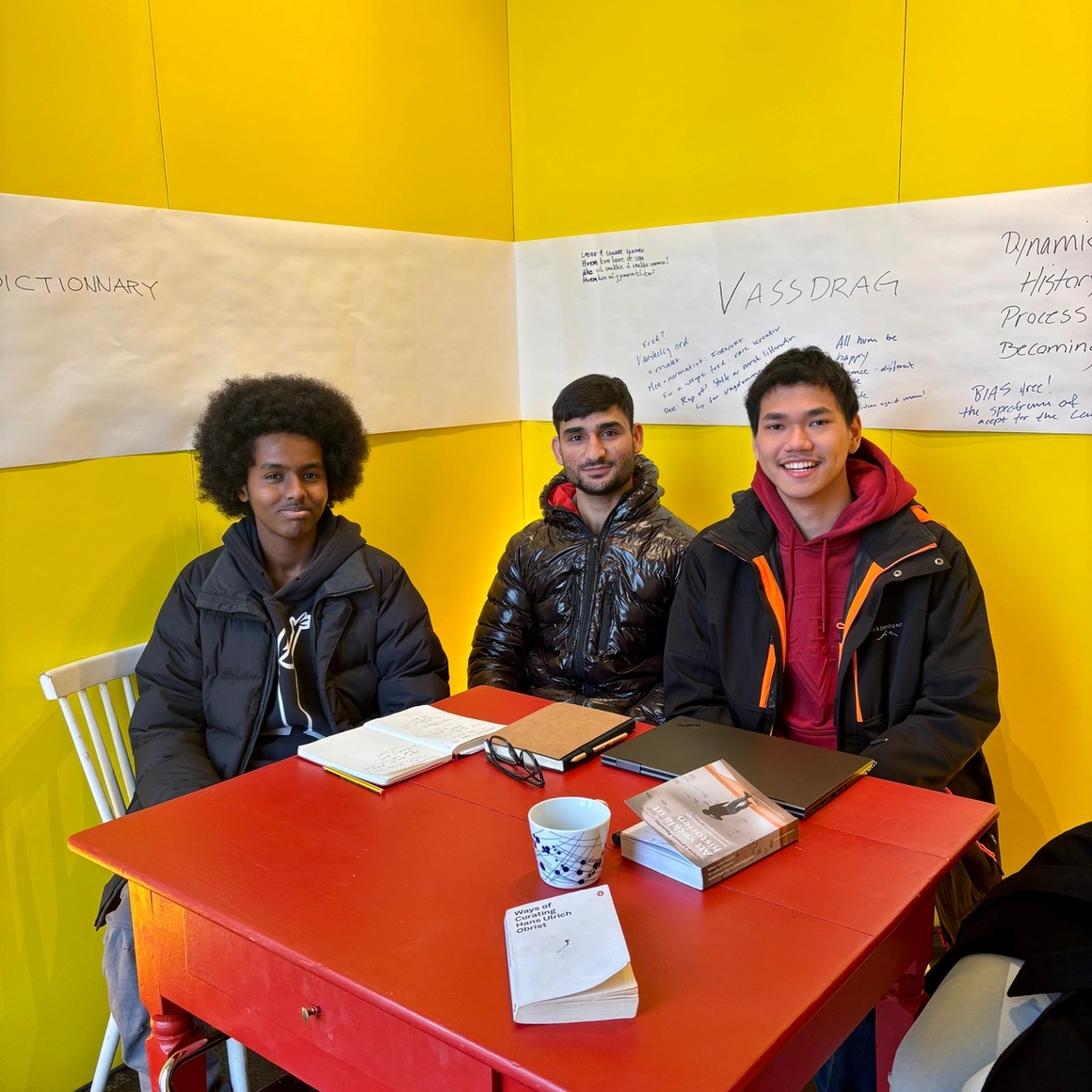 3 visitors that came into the open studio, looking through books at a table.