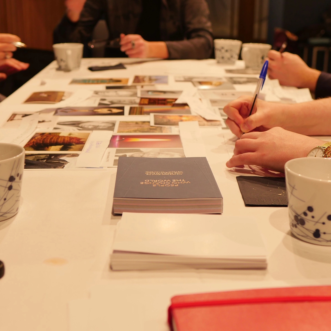 a table full of coffe cups and images and hands working-