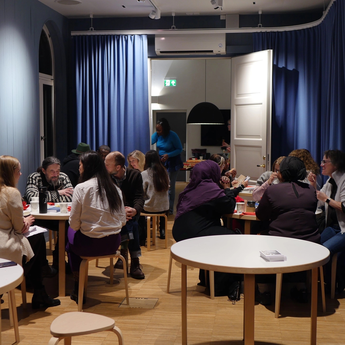 many workshop participants sitting around tables.