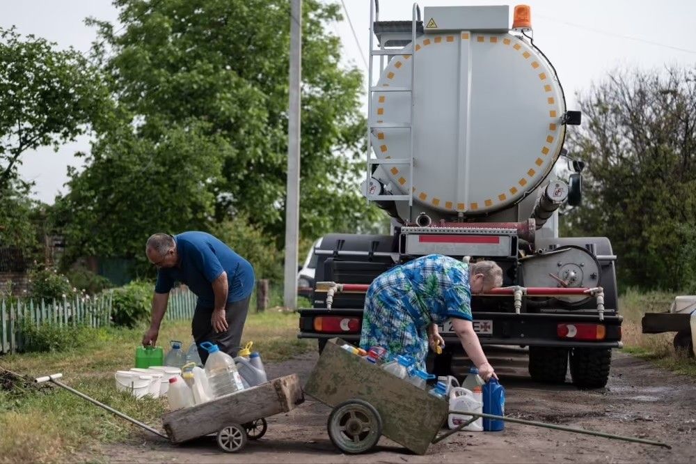 People who are gathering water into plastic containers.