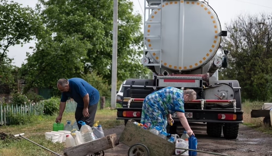 People who are gathering water into plastic containers.