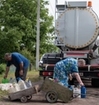 People who are gathering water into plastic containers.