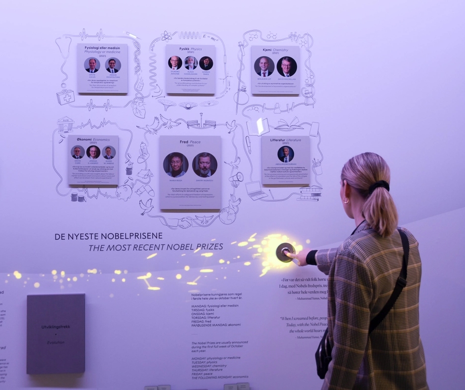 A woman presses a button on the exhibitions the wall and it lights up.