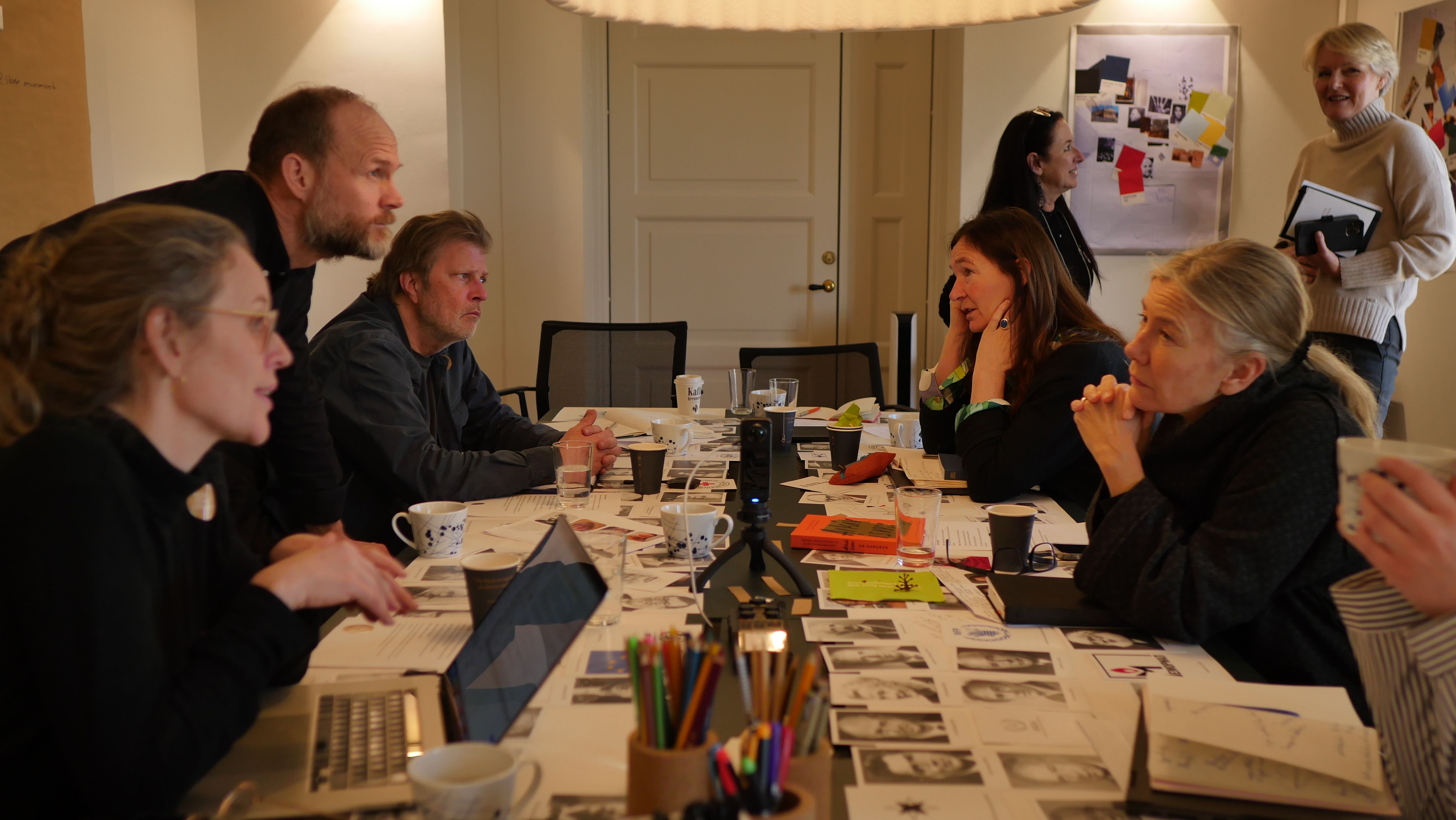 people around a table, discussing together.