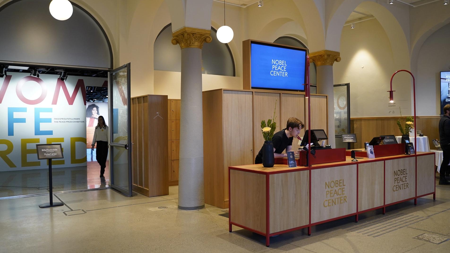 the entry hall at the museum, with front desk and a screen.