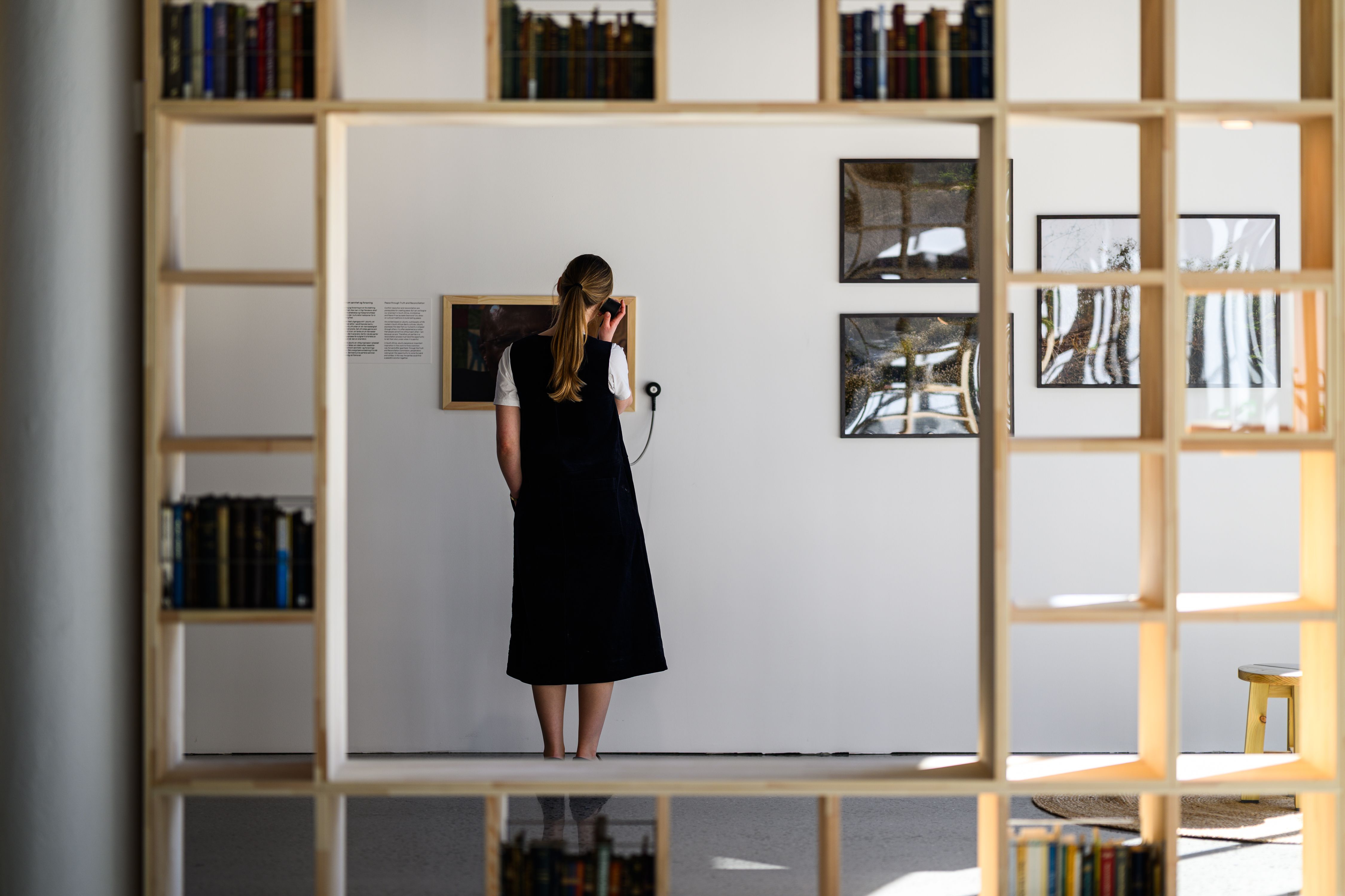 Fra utstillingen, en person som lytter til et lydspor og en bokhylle med bøker.