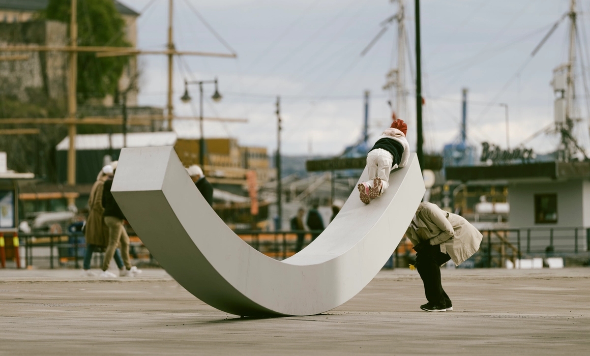 Fasaden til fredssenteret, med fredsbenken og to personer som leker på den.