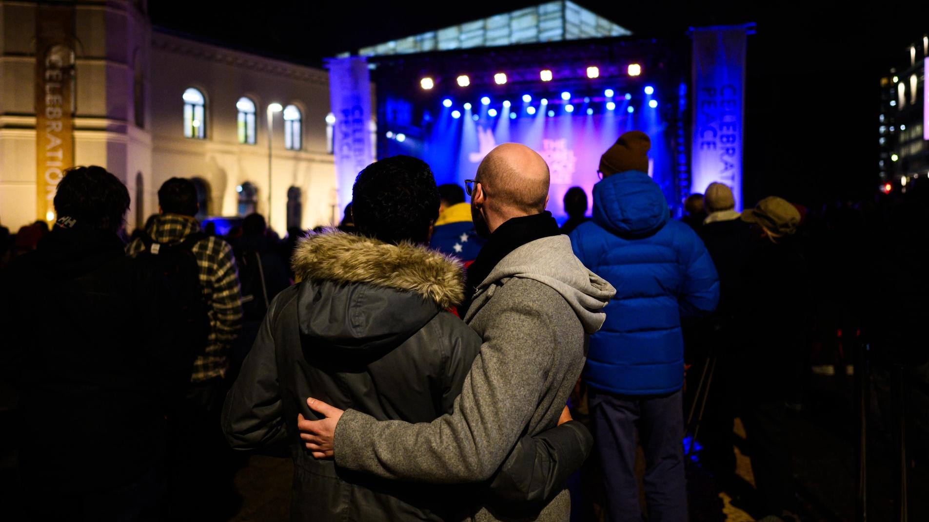 Publikum som ser på konserten, to personer som står inntil hverandre og ser på.