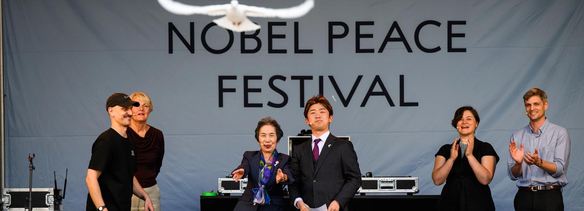 Dueslipp sermoni på scenen, 6 personer på scenen mens duen flyr.