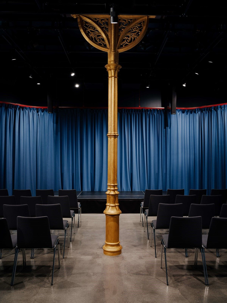 mandela rommet, med en utskymmet gullsøyle midt i rommet foran scenen.