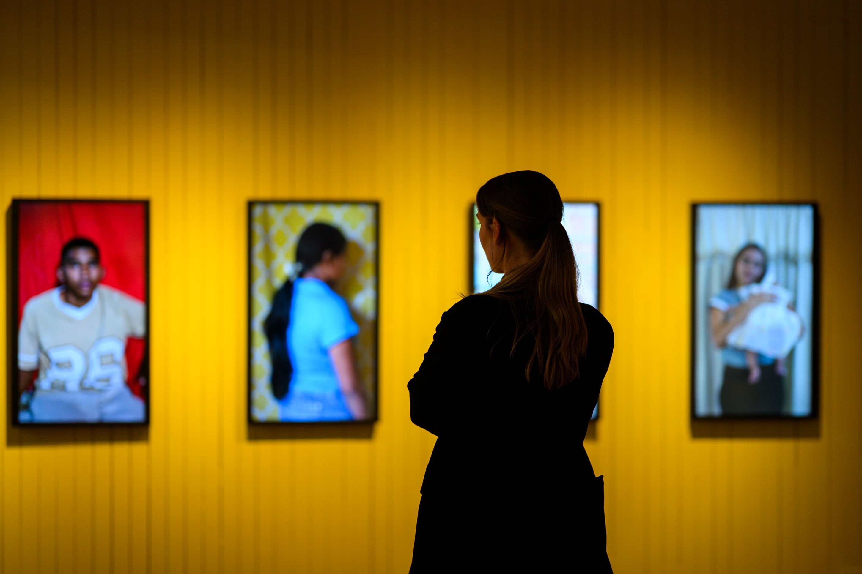 Fra fredsprisutstillingen, portretter av unge mennesker på en gul vegg.