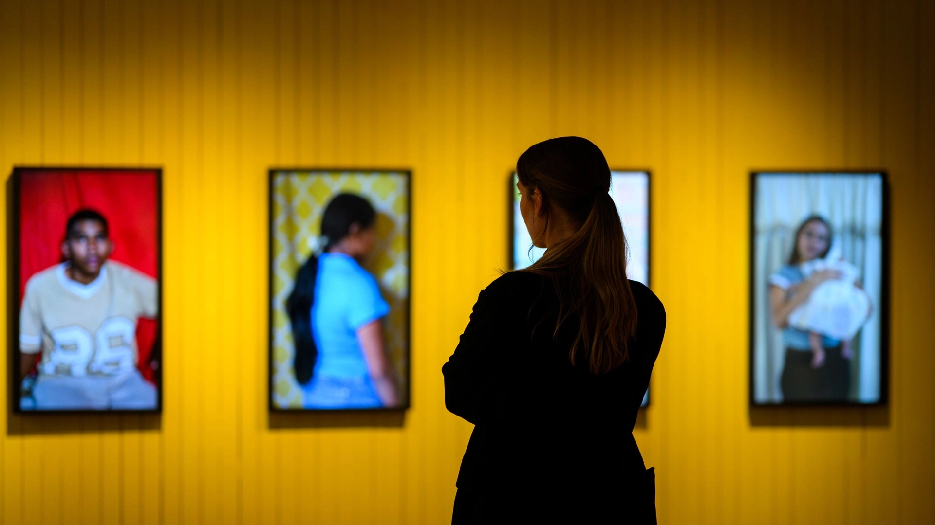 Fra fredsprisutstillingen, portretter av unge mennesker på en gul vegg.