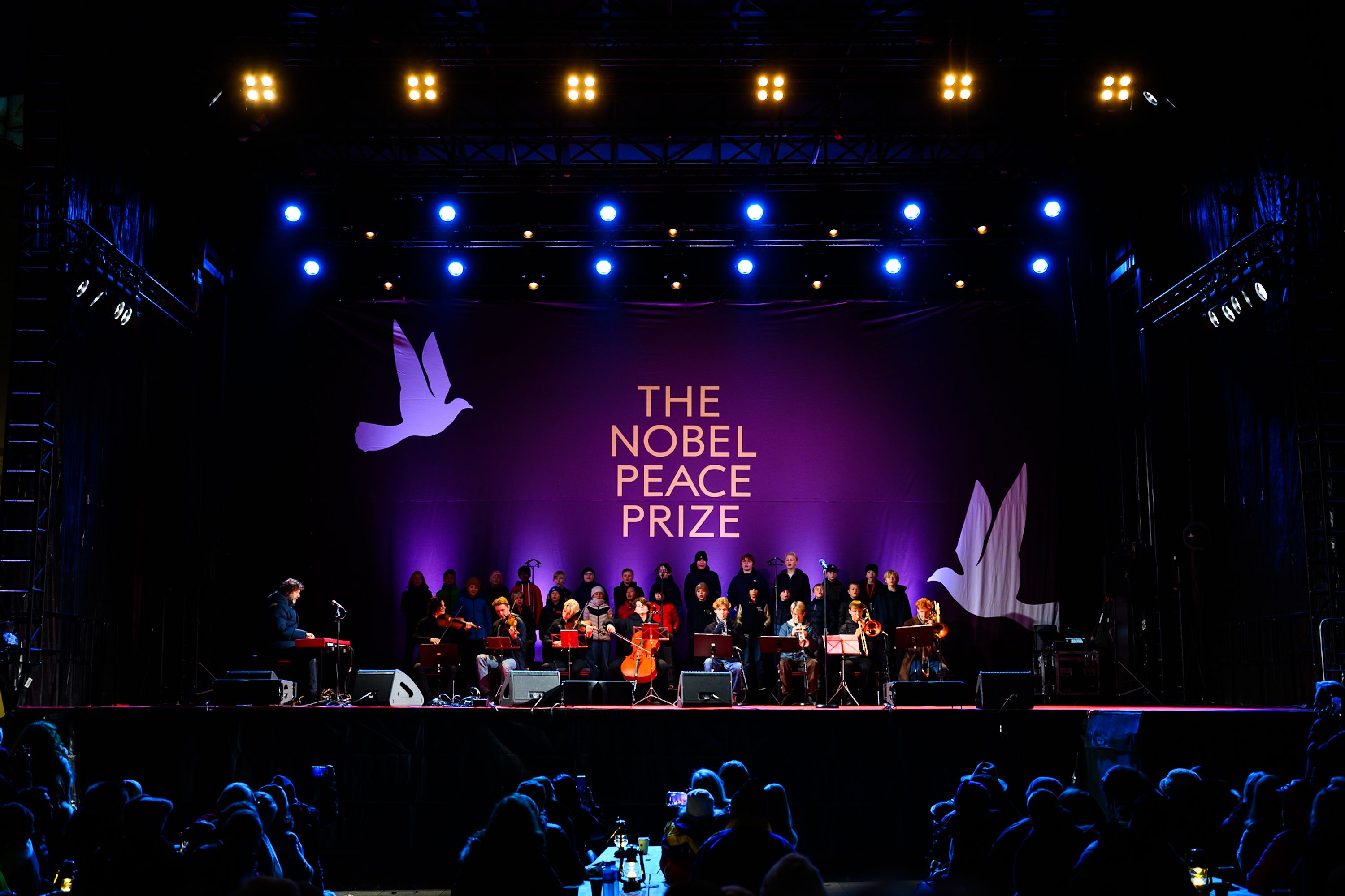 Scenen under bislett guttekor, stor logo i bakgrunnen som sier "the nobel peace prize"