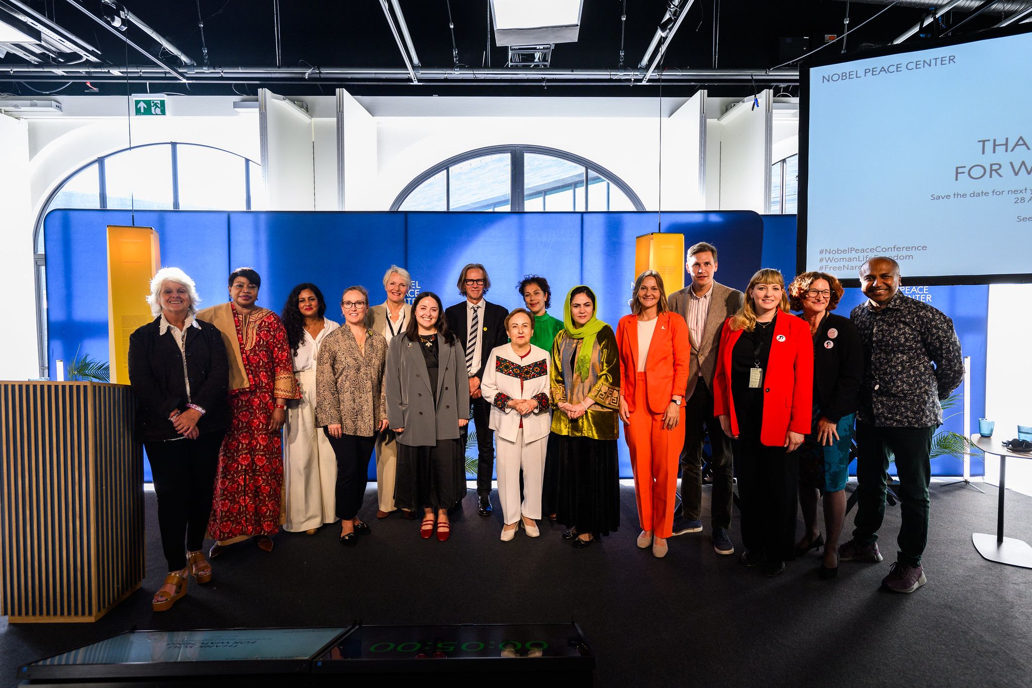 Gruppe med konferanse deltagere på scenen.