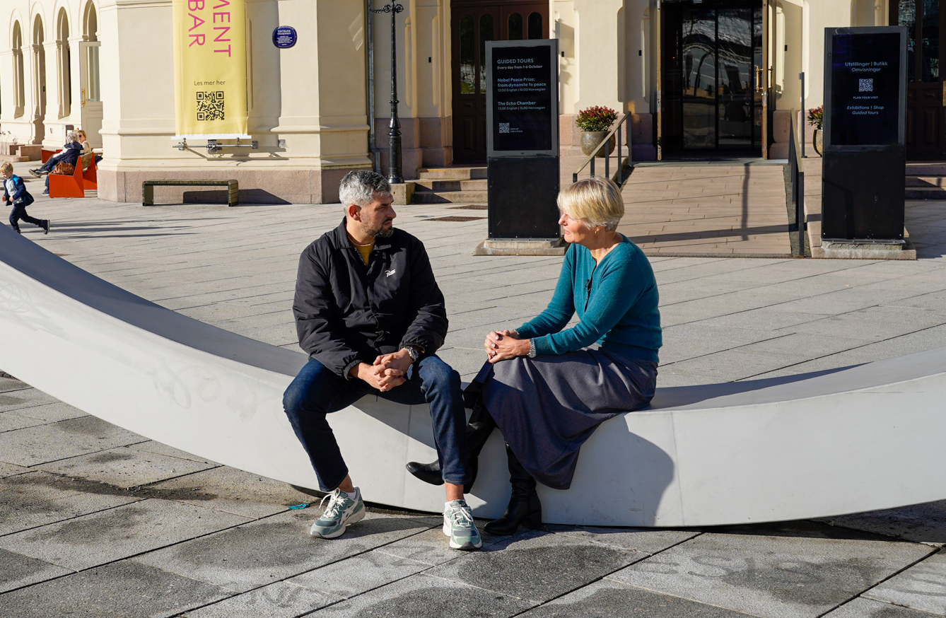 Leo Acjik og Kjersti Fløgstad i samtale på en benk