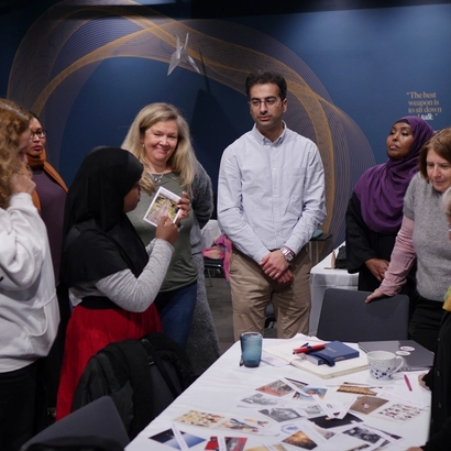 Fra workshop, mange mennesker samler seg rundt et bord med bilder.