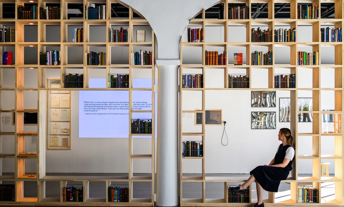 fra utstillingen paths to peace, bokhyller og person som sitter og ser på