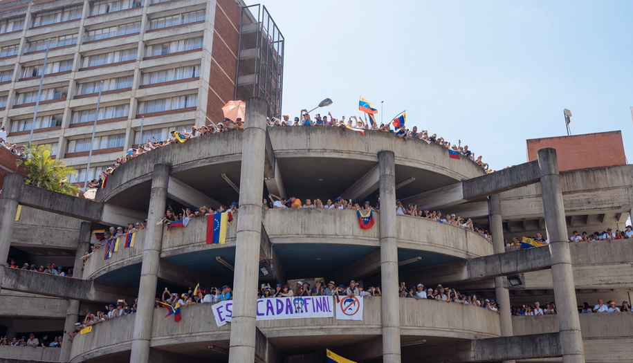 parkeringshus med protest av mange mennesker og plakater og flagg i venezuela.