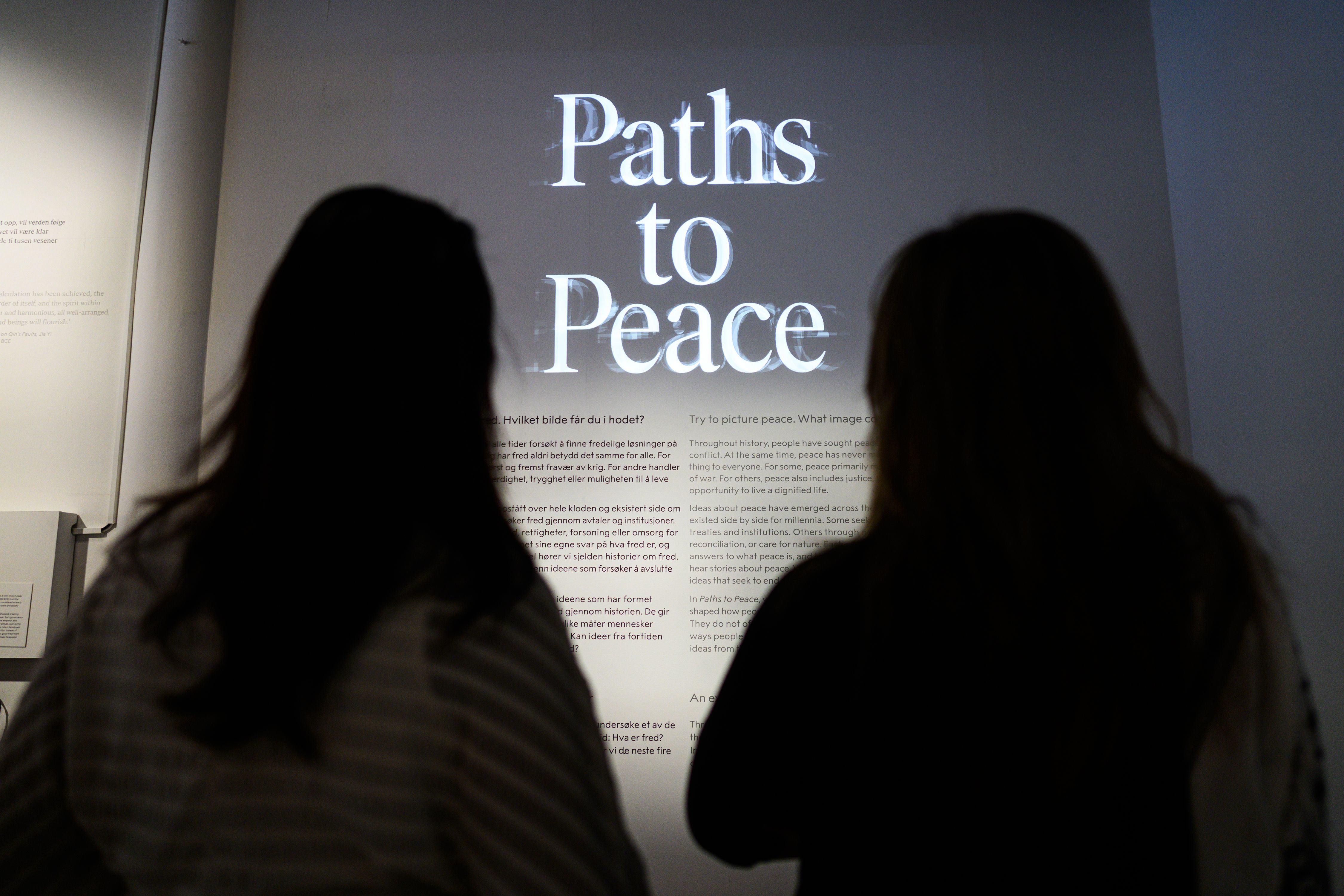 To personer som ser på en vegg med teksten "paths to peace"