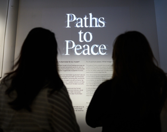 To personer som ser på en vegg med teksten "paths to peace"