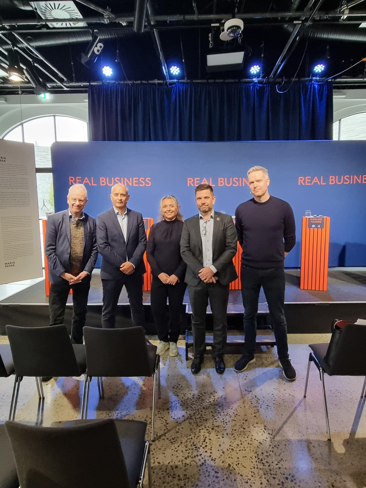 fra arrangement, folk som poserer foran scenen.