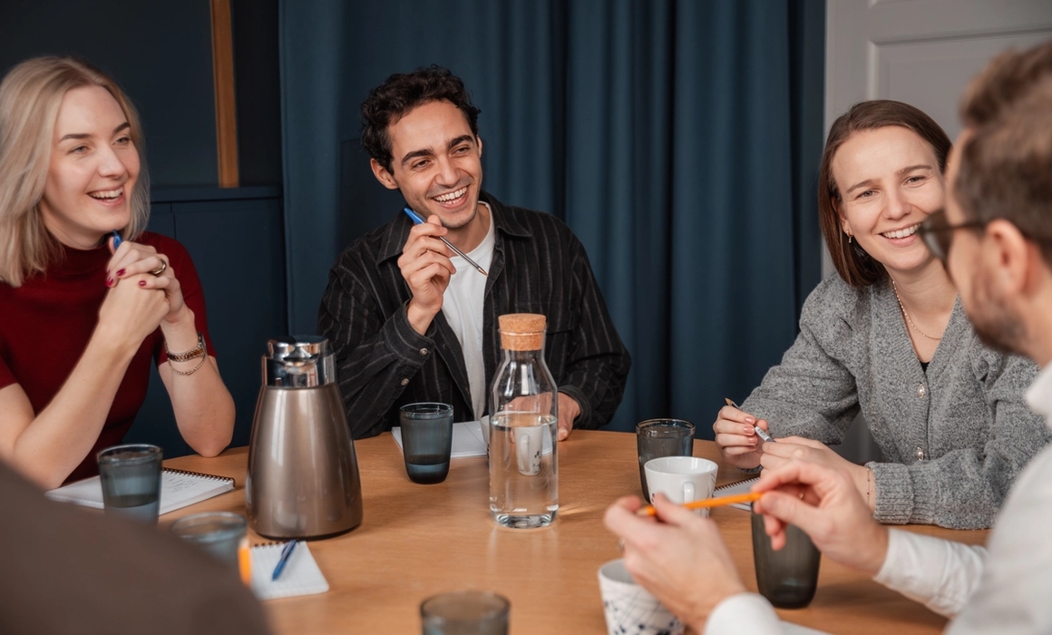 personer som sitter rundt et bord og har god stemning og prater