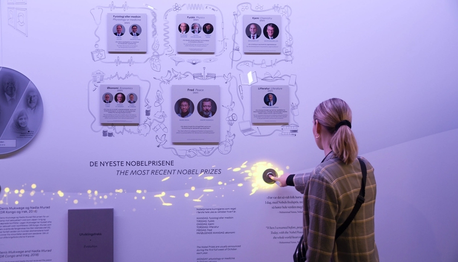 En kvinne trykker en knapp slik at den lyser opp på veggen i utstillingen.