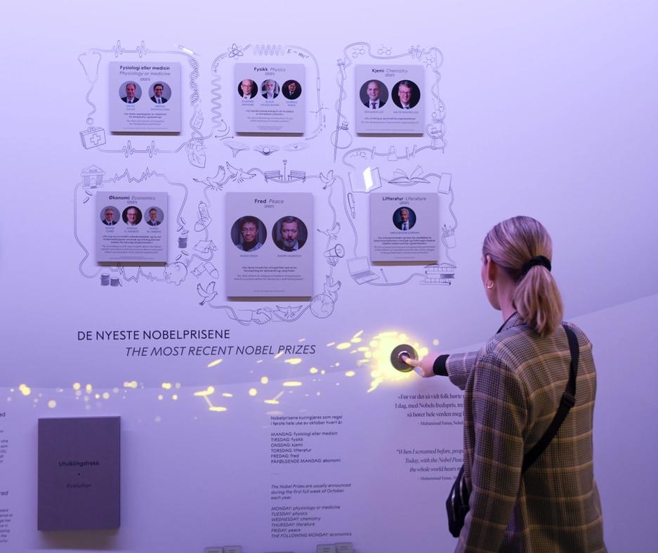 En kvinne trykker en knapp slik at den lyser opp på veggen i utstillingen.
