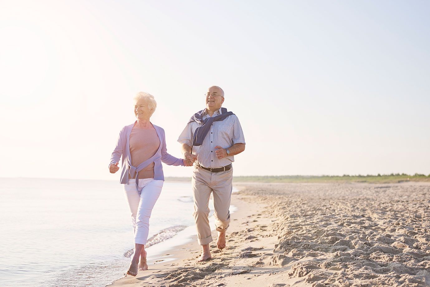 Older couple walking on the beach as part of an active lifestyle supporting healthy aging.