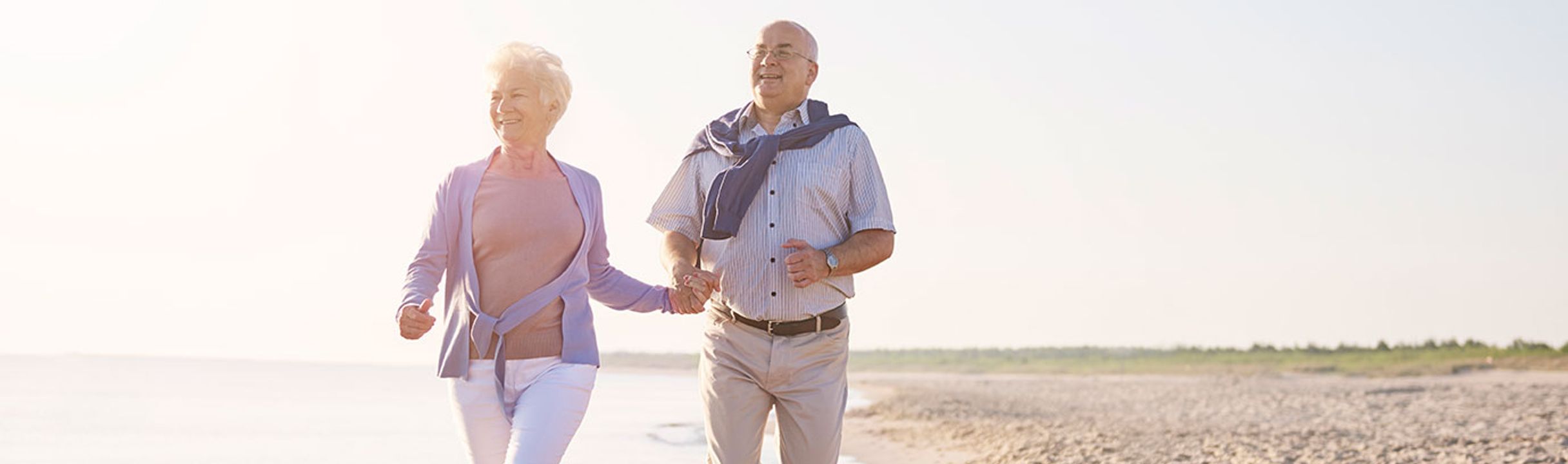 Older couple walking on the beach as part of an active lifestyle supporting healthy aging.