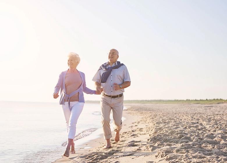 Older couple walking on the beach as part of an active lifestyle supporting healthy aging.