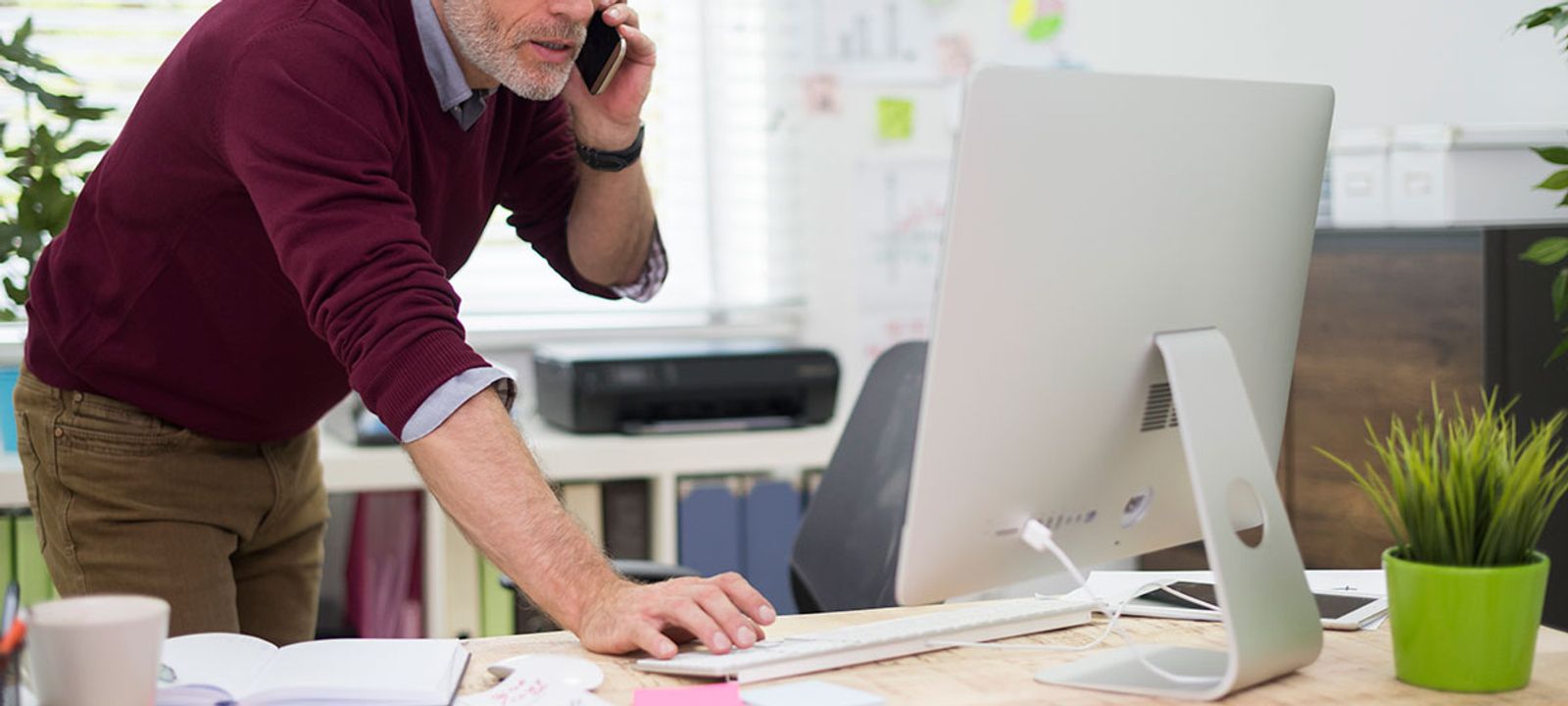 Busy professional multitasking at his desk, highlighting the importance of healthcare for busy professionals.