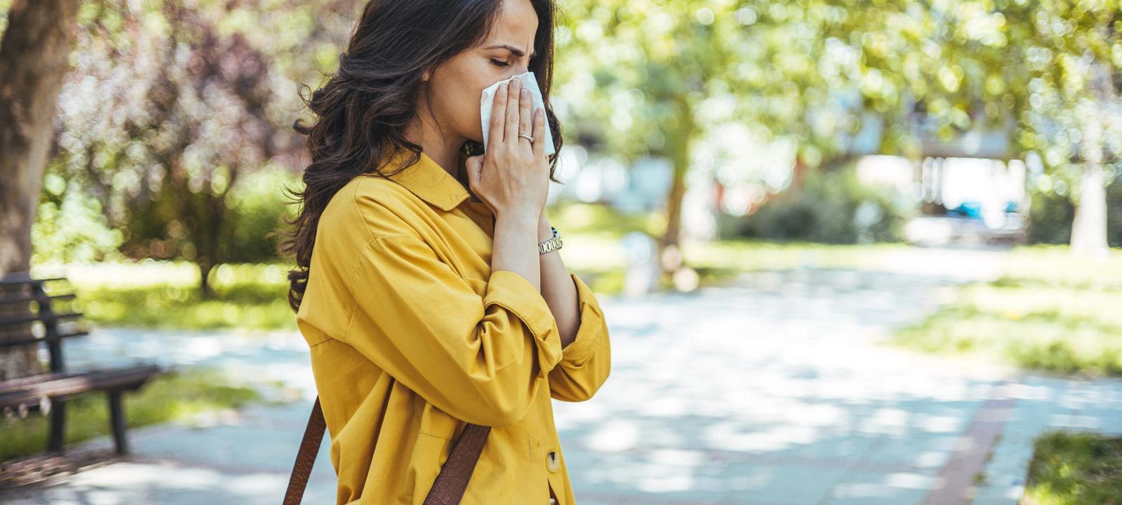 woman sneezing outdoors showing need for immune system support