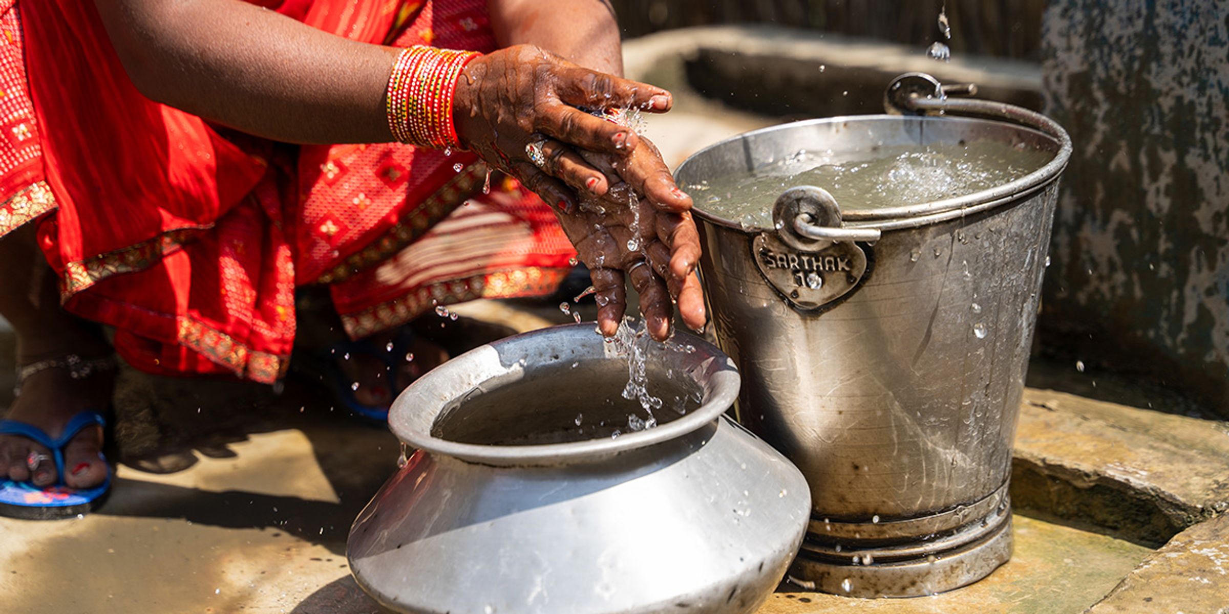 Woman in Nepal washing her hands in a bucket with clean water