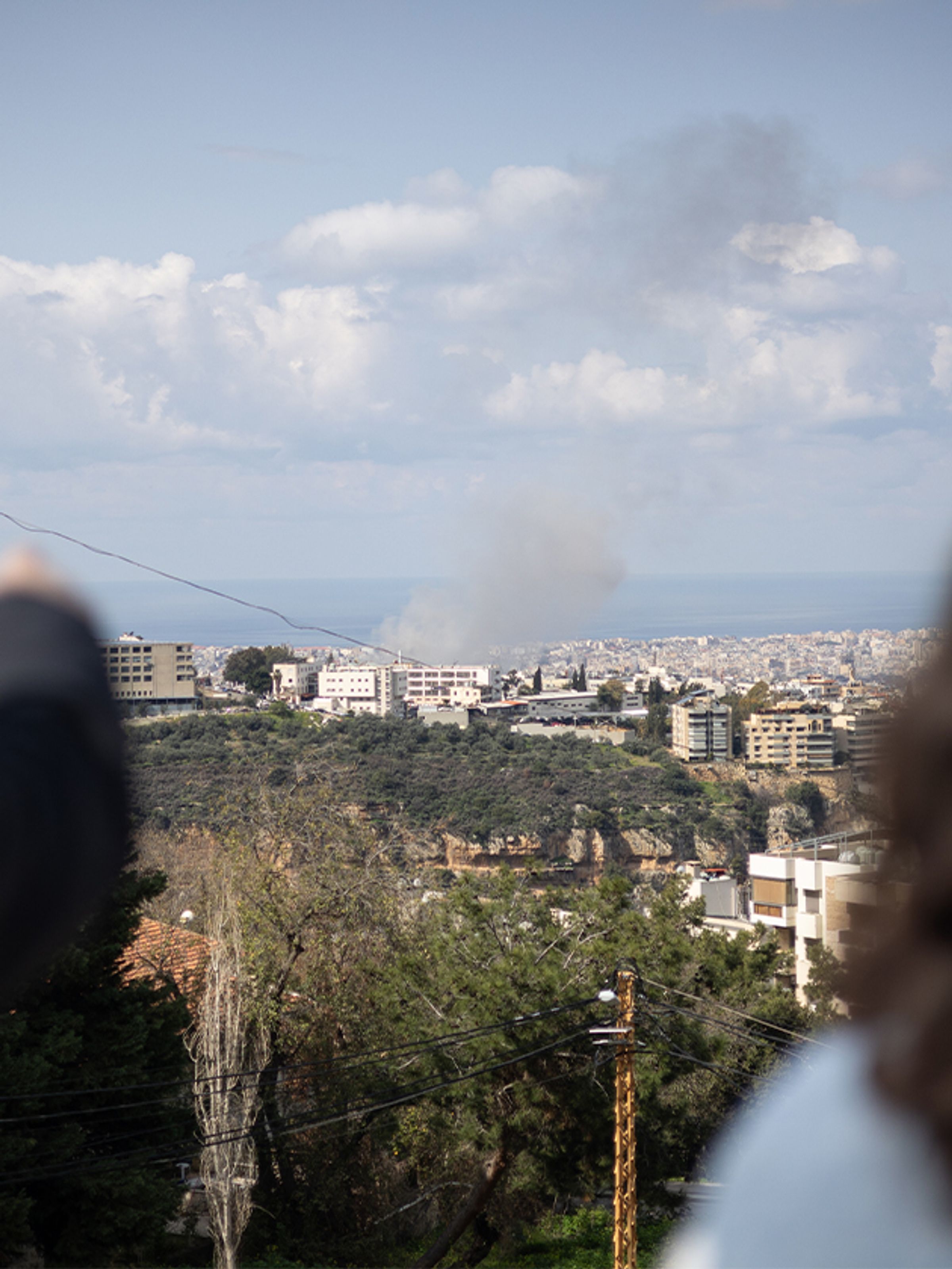 Smoke rising over a coastal city in Lebanon, seen from a hillside