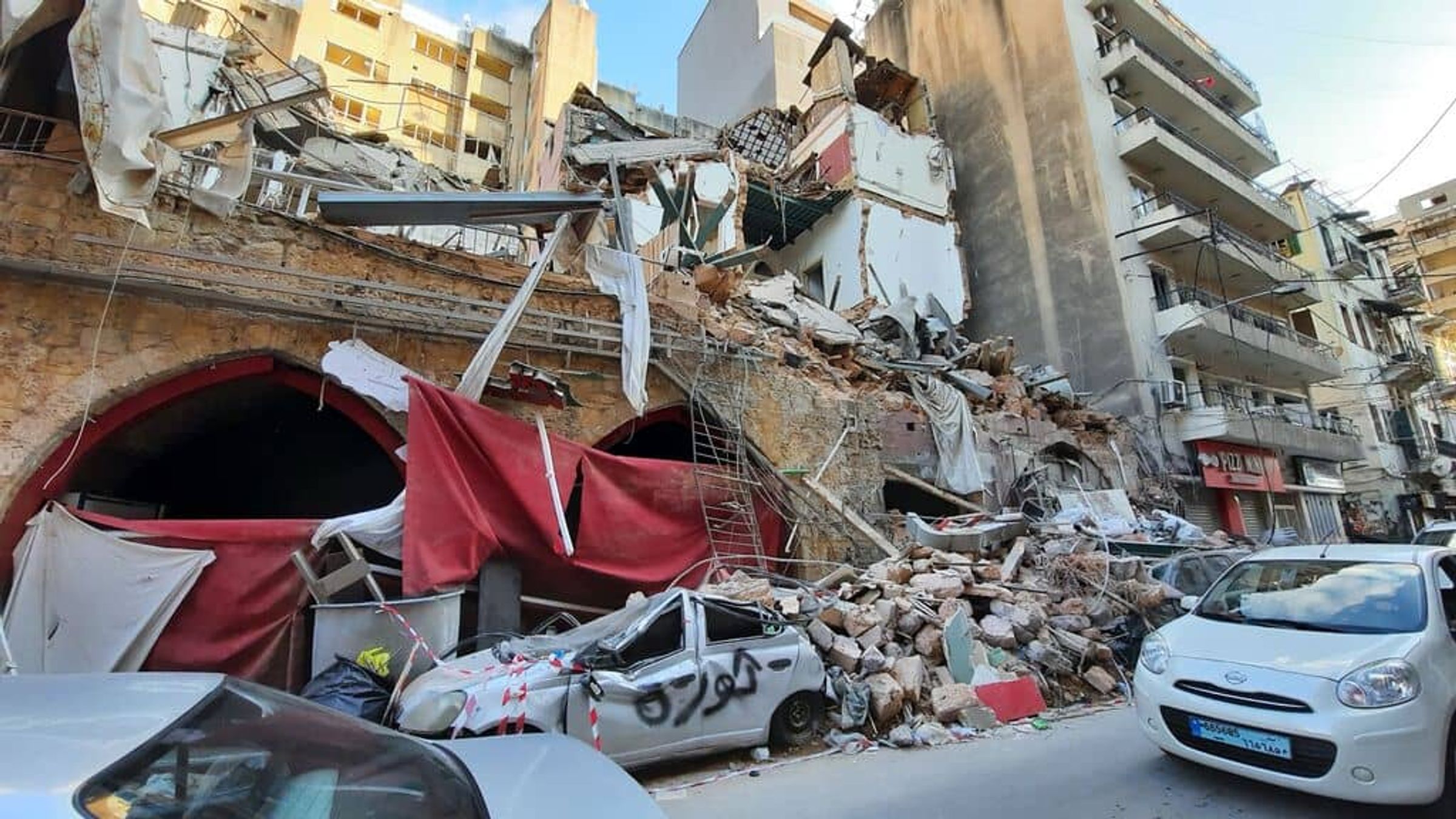 Collapsed buildings and crushed cars on a damaged city street