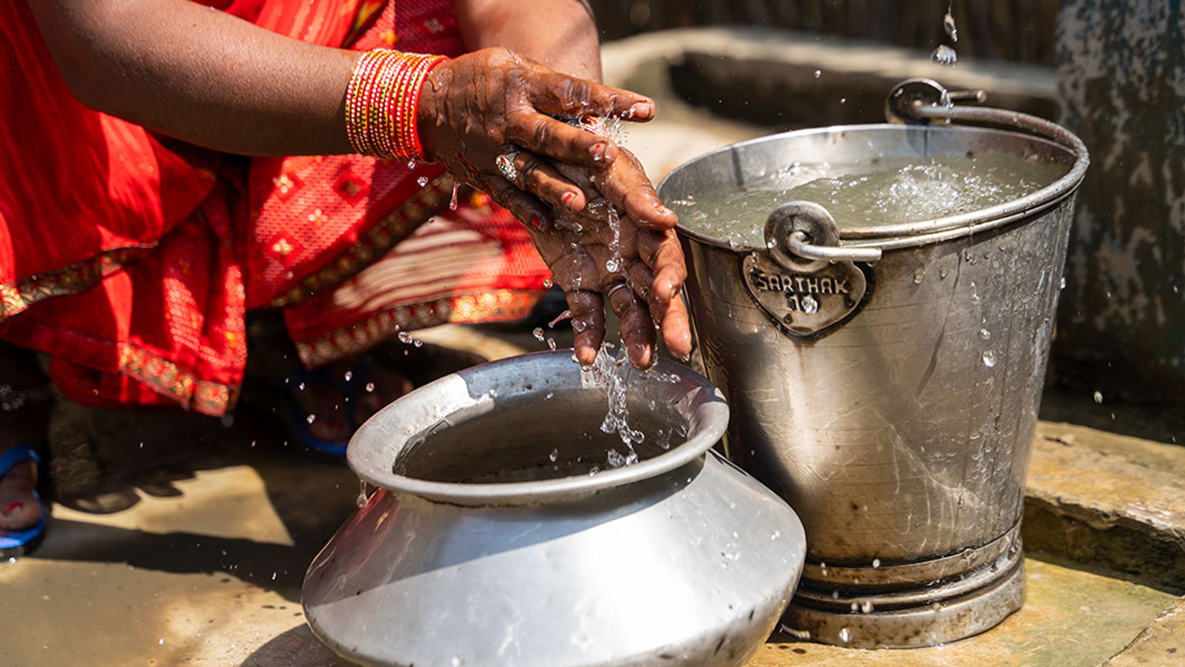 Woman in Nepal washing her hands in a bucket with clean water