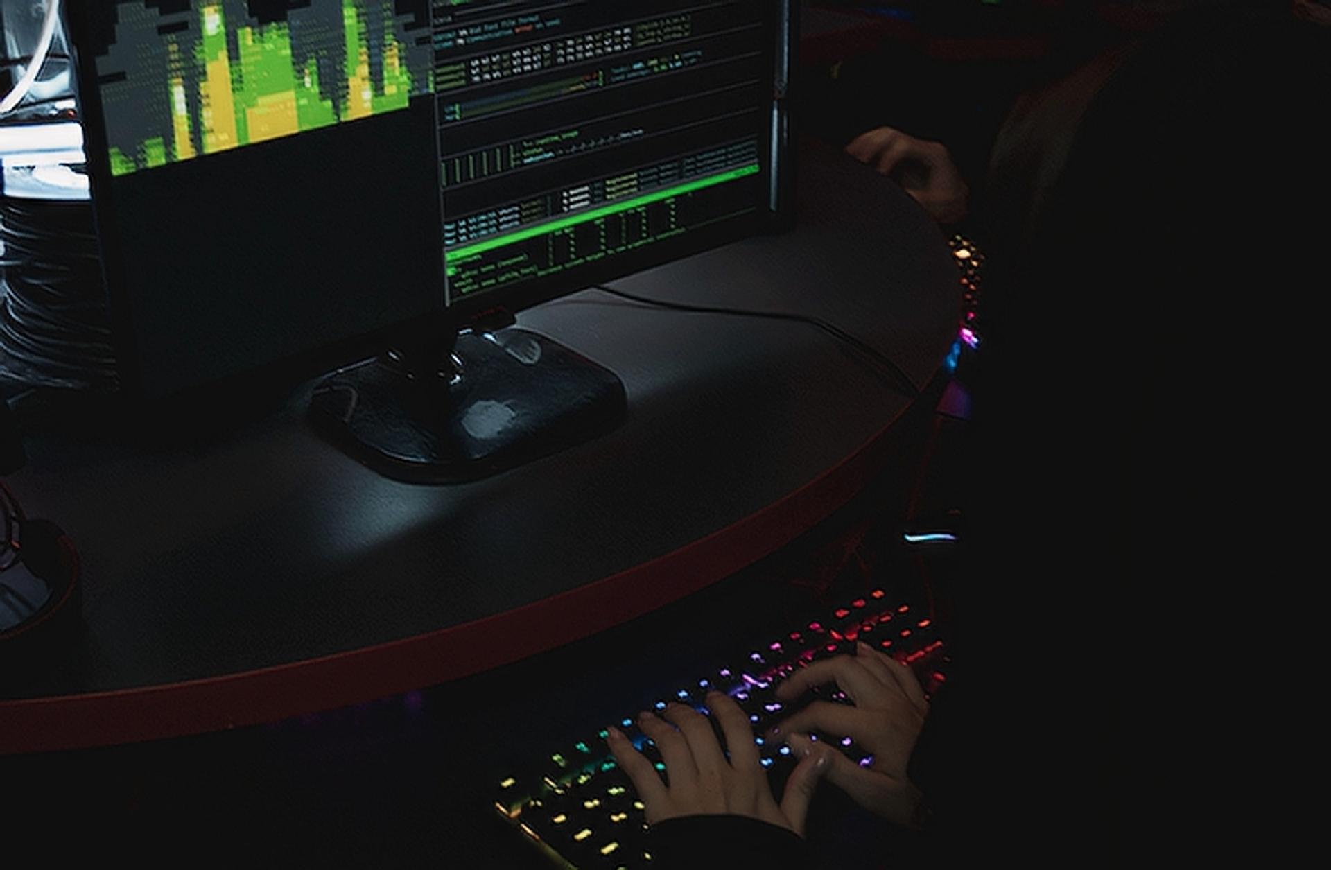 Hooded person using their computer in the dark