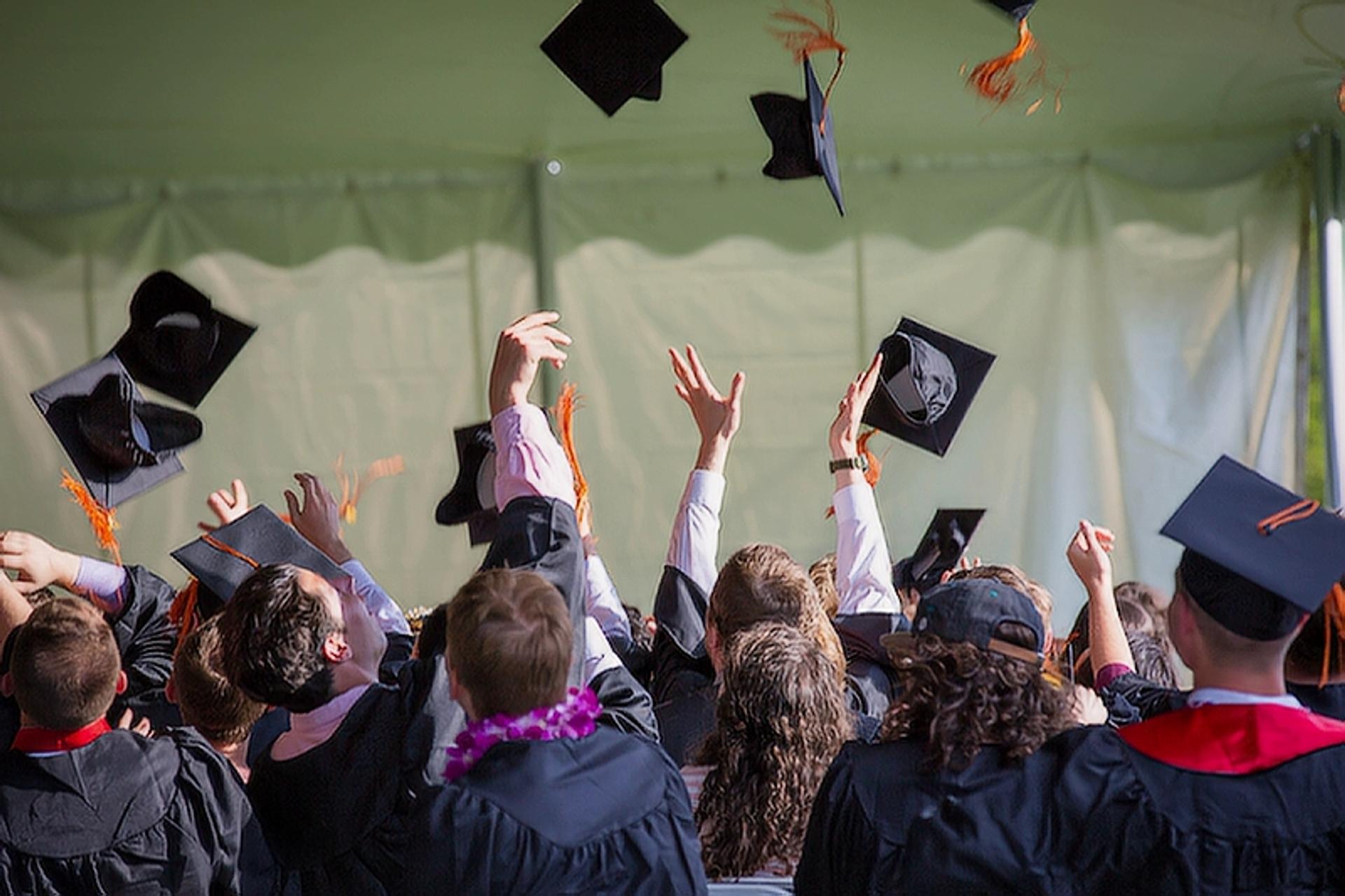 An image of students throwing cap in the air after graduation