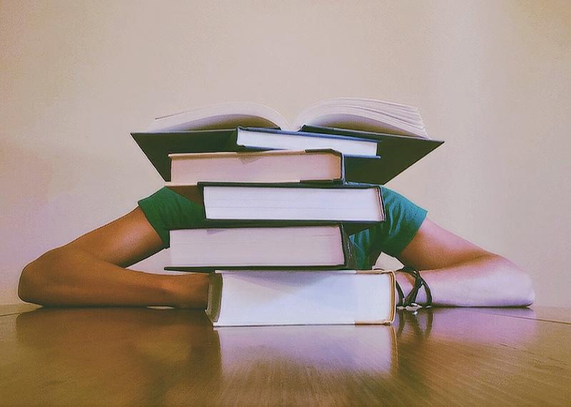 Student with their head down in front of a stack of school books