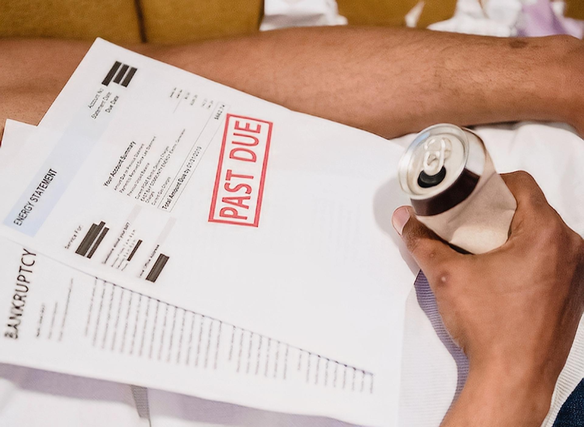 Man laying with past due bills on top