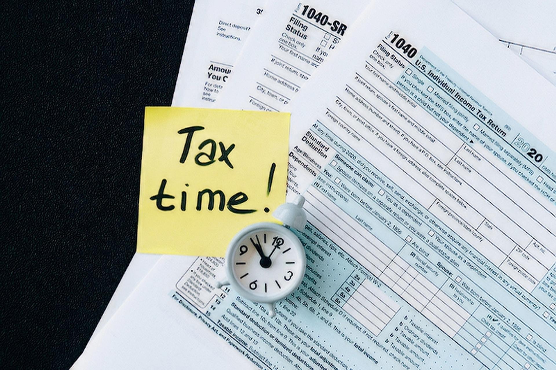 Tax documents with a small clock and a sticky note that says "Tax time"