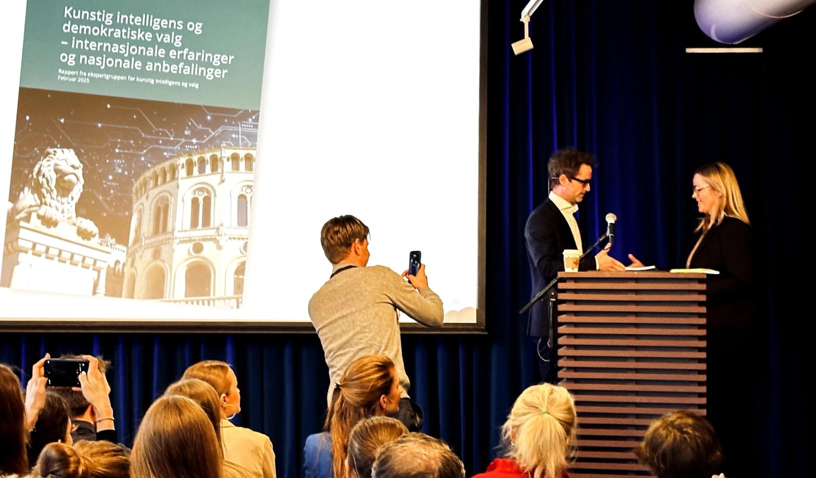 Niels Nagelhus Schia som har ledet ekspertgruppen, overrekker rapporten til kommunal- og distriktsminister Kjersti Stenseng.