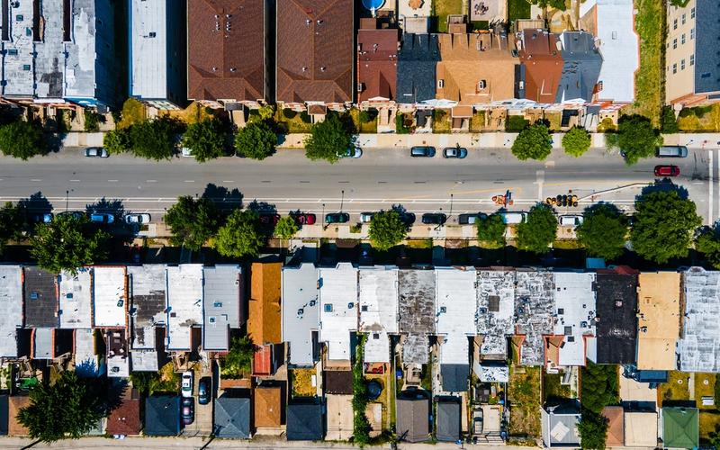 Aerial view of a tree-lined Chicago neighborhood street with rows of residential rooftops on both sides