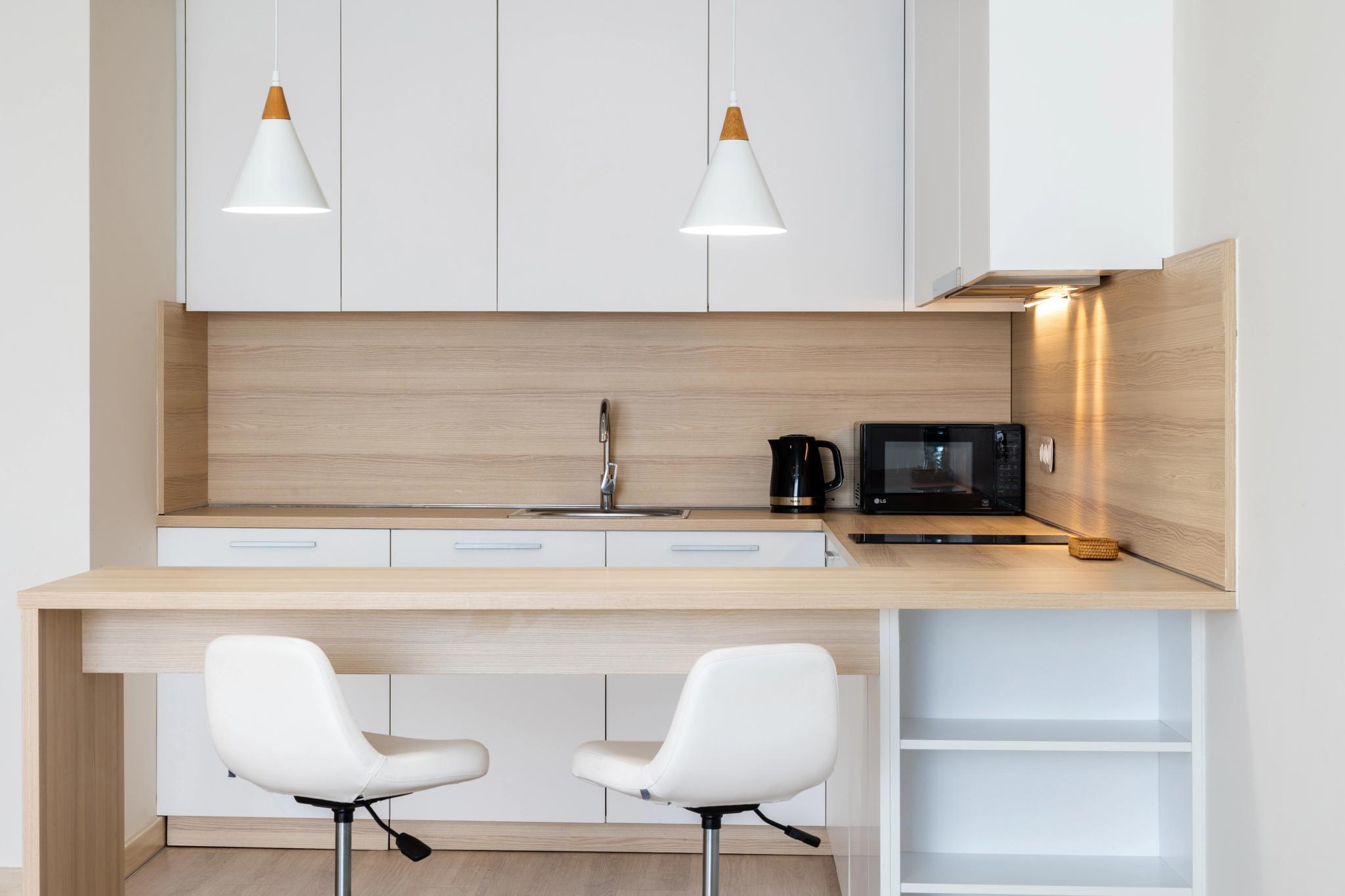 Tor'Re Astana hotel room: modern kitchenette with white cabinetry, wooden accents and professional interior photography in Astana