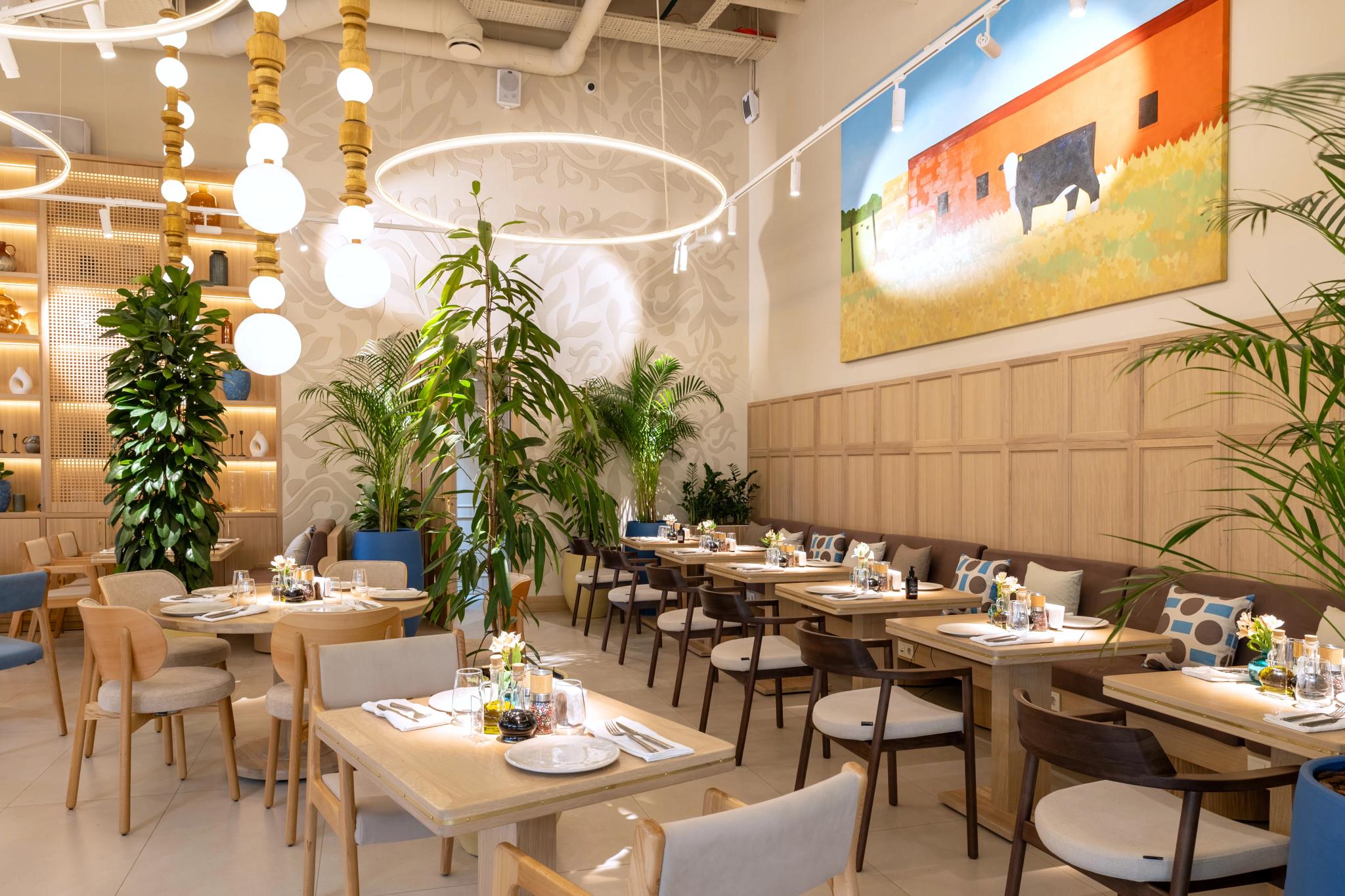 Modern restaurant interior design of Syrovarnya in Astana featuring wooden furniture, green plants and neon lighting – professional interior photography Kazakhstan