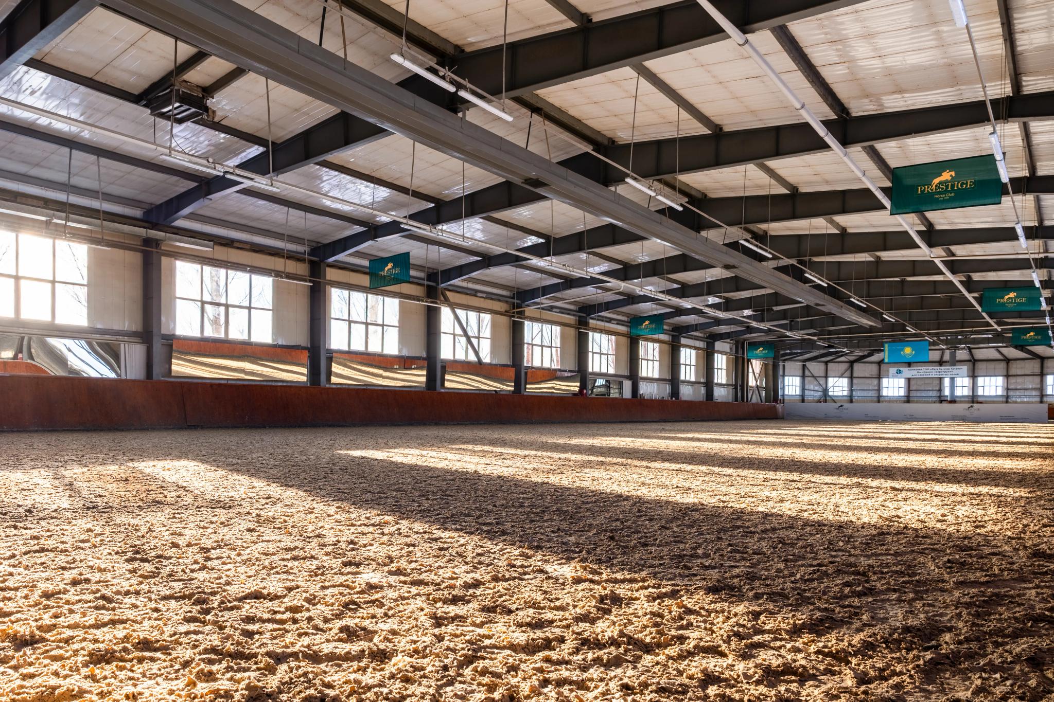 Spacious indoor riding arena at Prestige equestrian club with sand flooring, architectural photography Astana